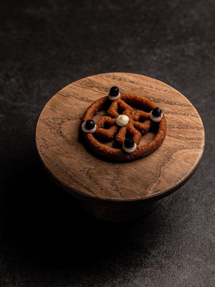 Gourmet deep-fried dessert with cream and berry dots on wooden plate
