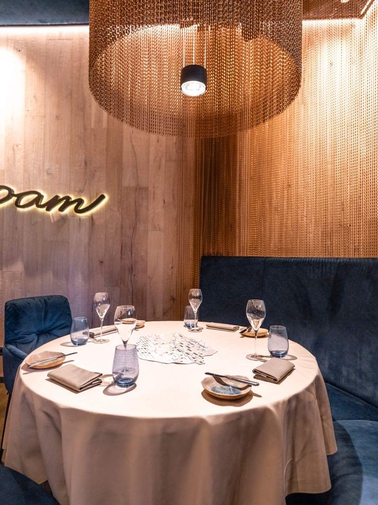 Eleganter Restauranttisch mit blauer Samtsitzbank und Holzverkleidung mit dahoam-Schriftzug