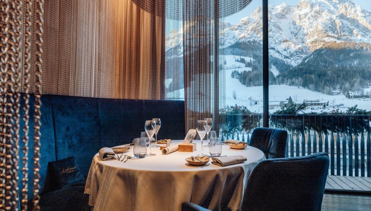 Eleganter Restauranttisch für Fine Dining mit Bergblick durch großes Fenster