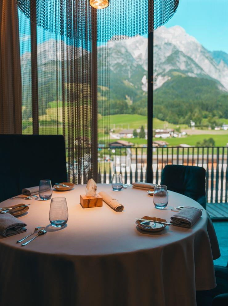 Eleganter Restauranttisch am Fenster mit Blick auf die Berge im Hintergrund