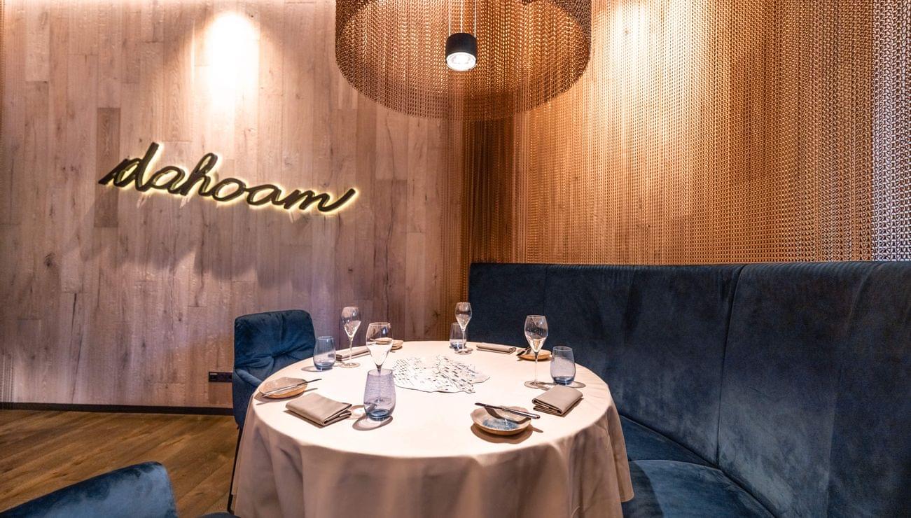 Eleganter Restauranttisch mit blauer Samtsitzbank und Holzverkleidung mit dahoam-Schriftzug