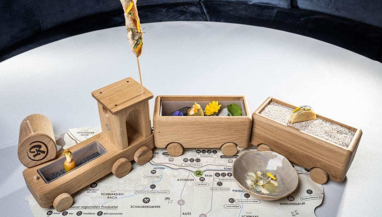 Gourmet appetizers served in wooden toy train on Alpine regional map