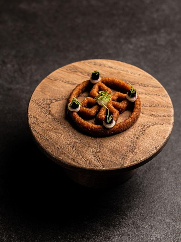 Gourmetbrezelring mit Creme und Kräutern auf Holzteller serviert